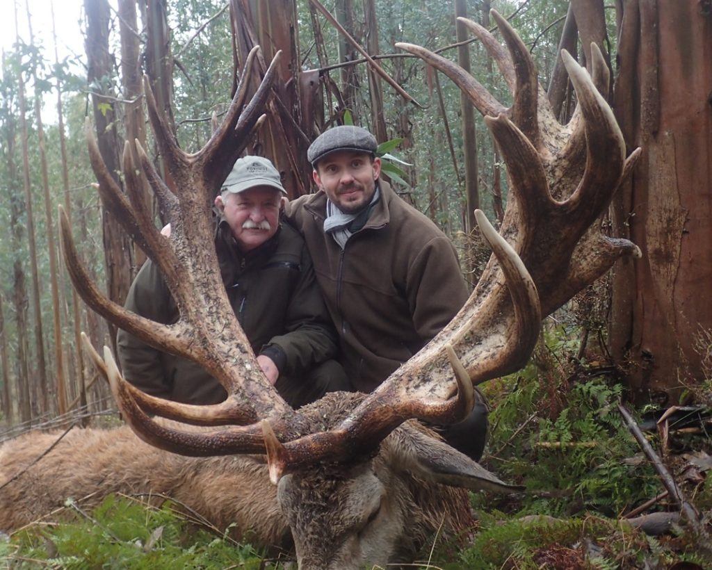 A couple of men holding their deer trophy.